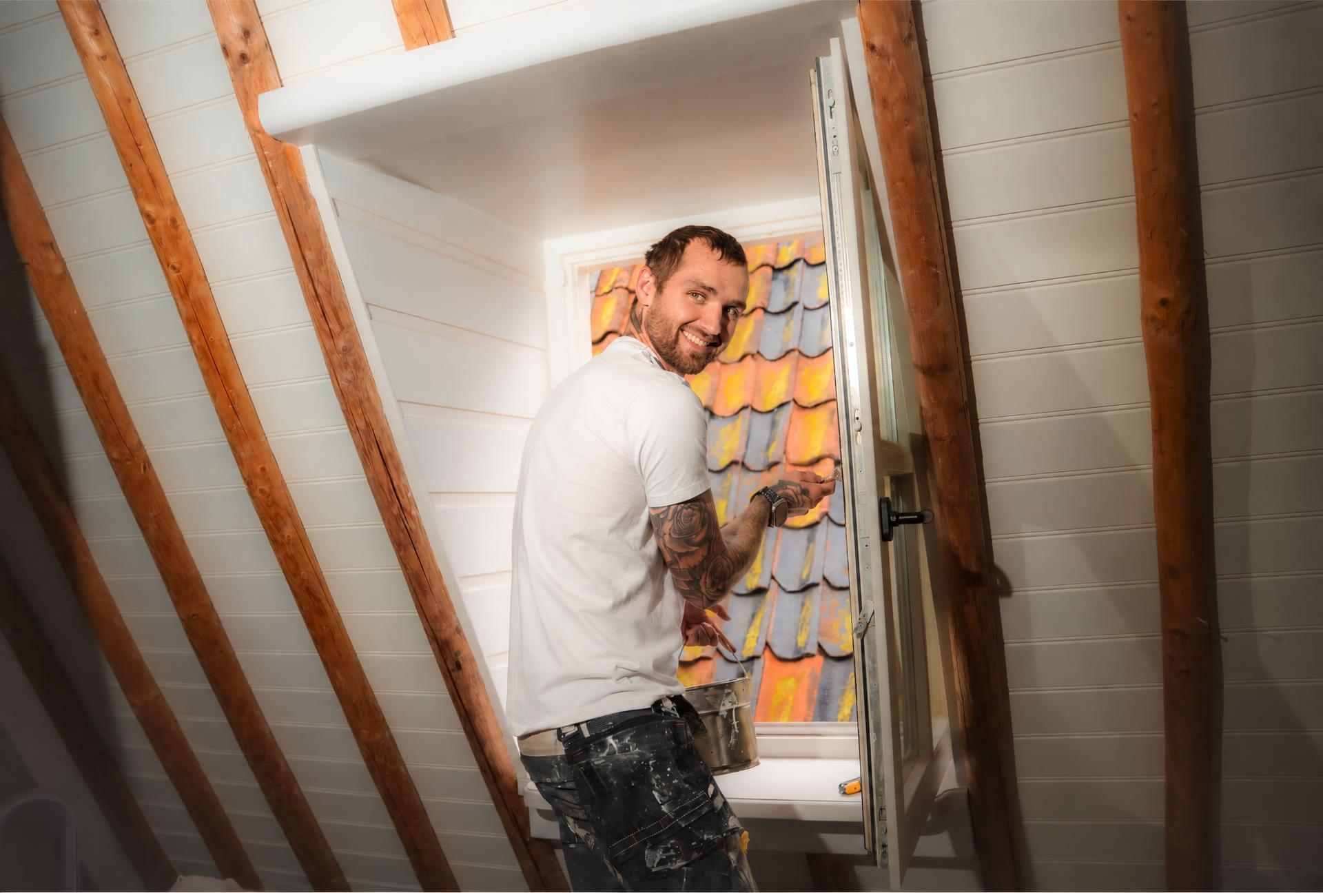 Schilder aan het werk bij een open dakkapel, met verfblik en kwast